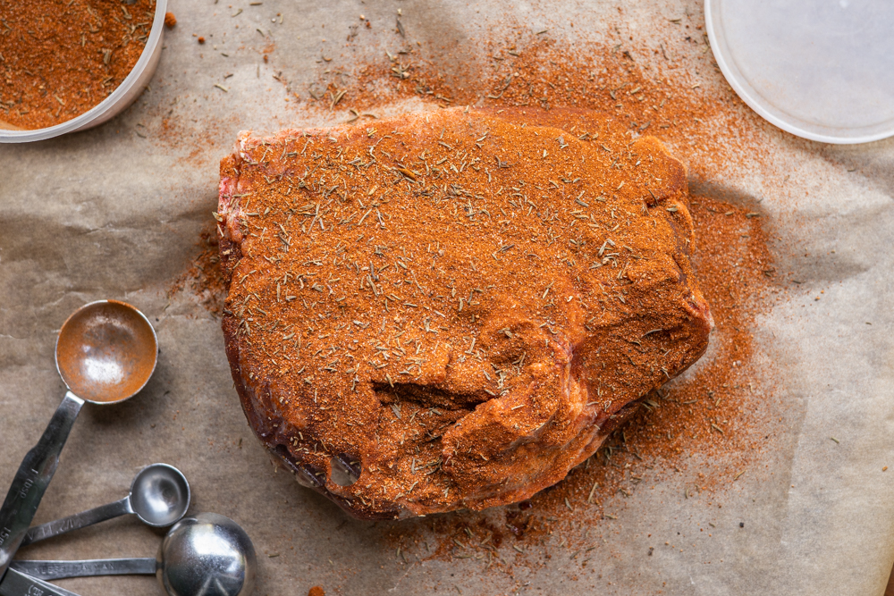 Rubbing a goat shoulder with blackening spice