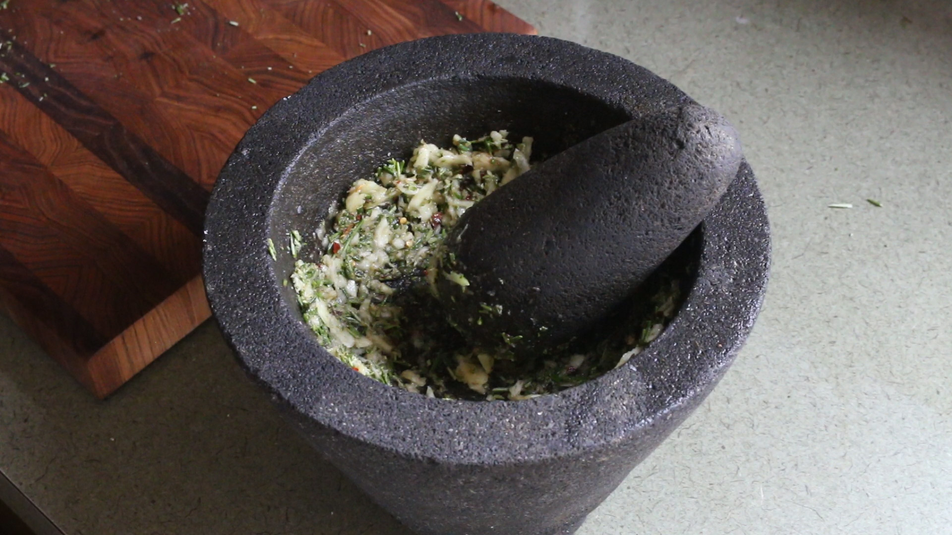 Grinding garlic, rosemary and chili with oil in a molcajete