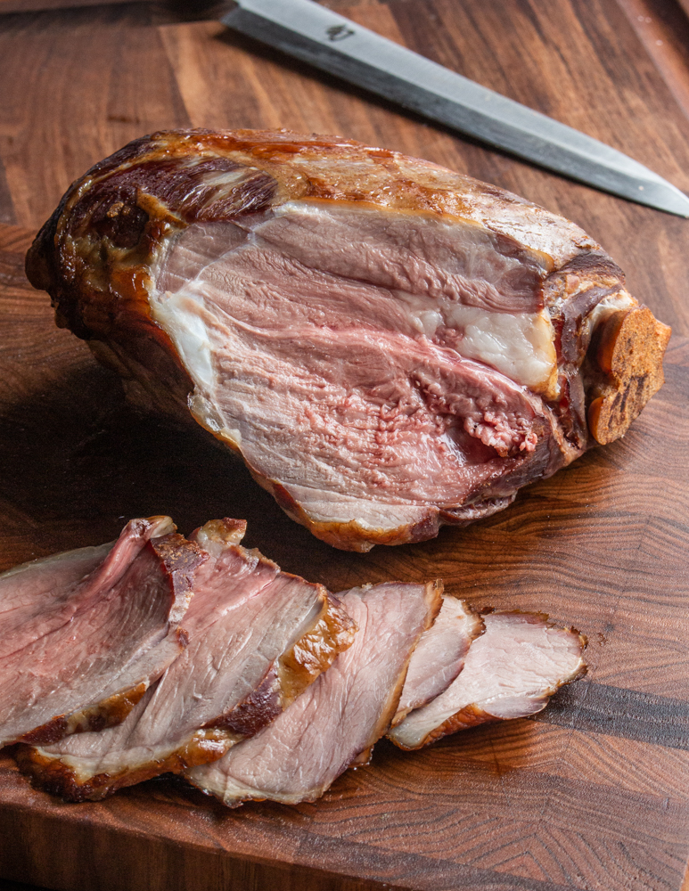 Sliced, smoked brined leg of lamb being carved