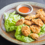 breaded lamb fries on a bed of lettuce with sauce